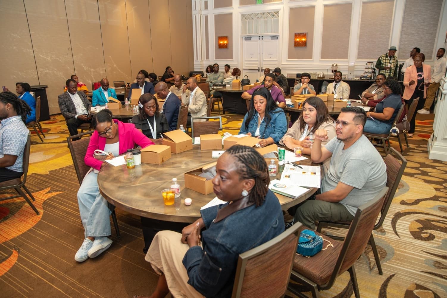 Attendees working at round tables in the ballroom