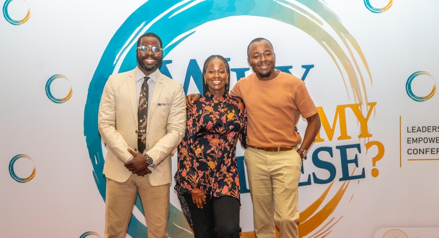 Three attendees at the conference backdrop